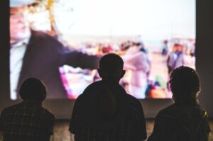 Three people sit in front of a screen watching a movie at Warriewood cinema